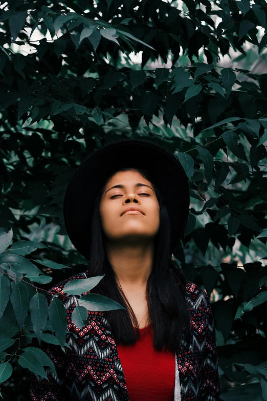 a woman with her eyes closed in the bushes