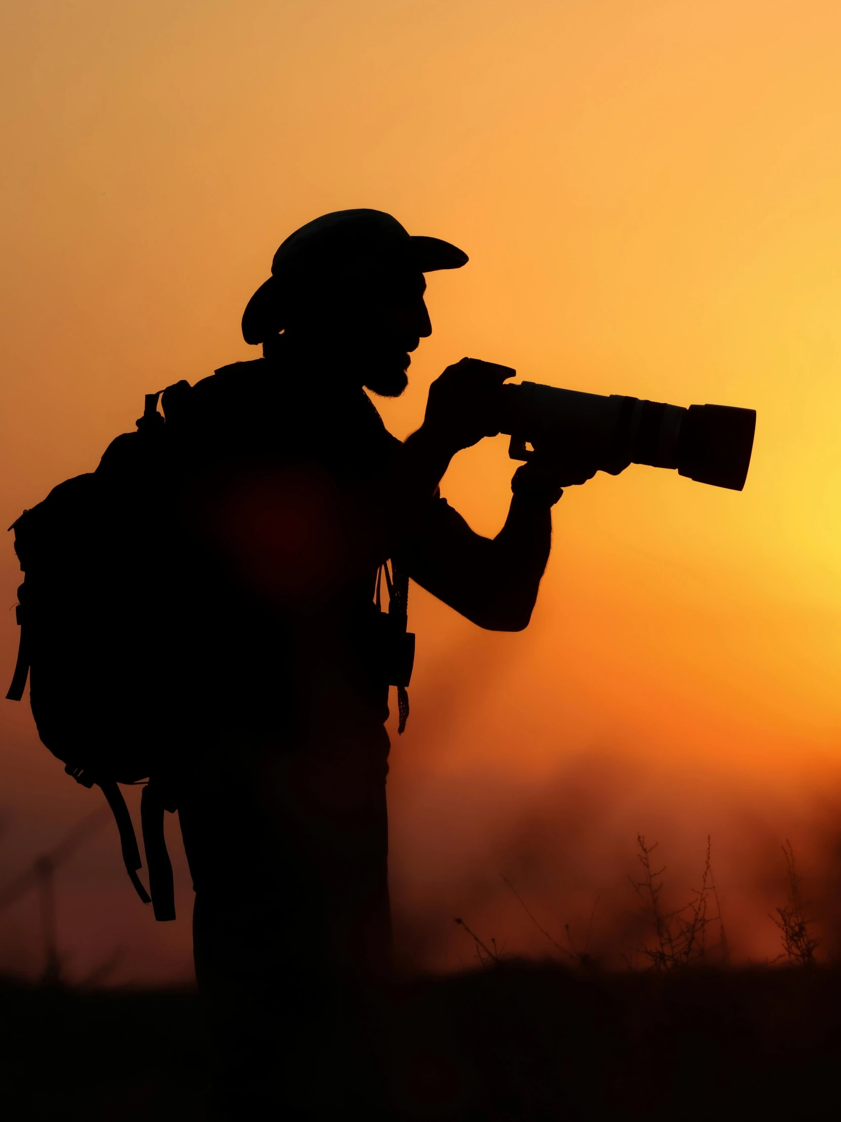 silhouette of a pographer with backpack using a camera