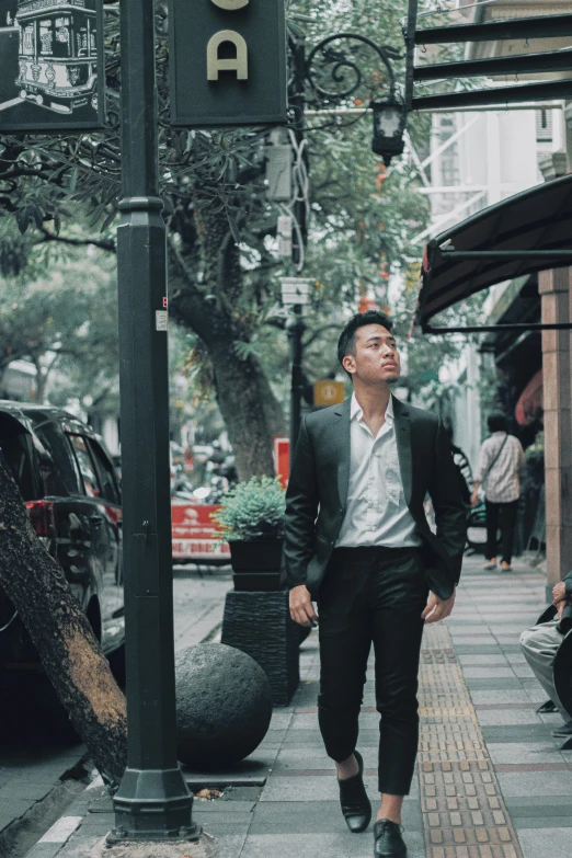 man in suit walking through the rain under a street sign