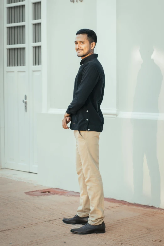 a man wearing khaki stands in front of a house