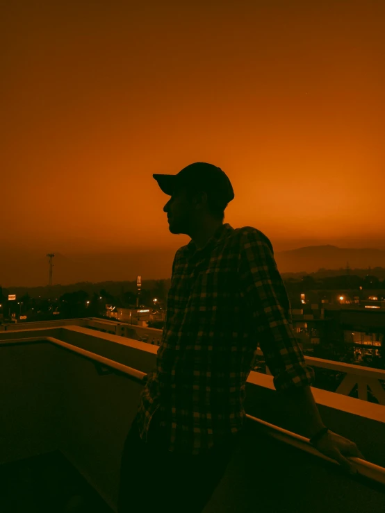 the man stands on top of the building near the sunset