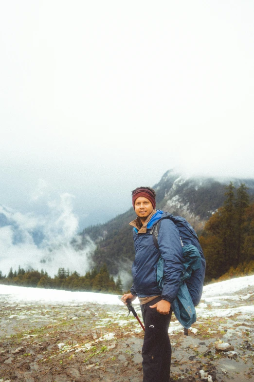 a young man with his backpack at the top of a snowy hill