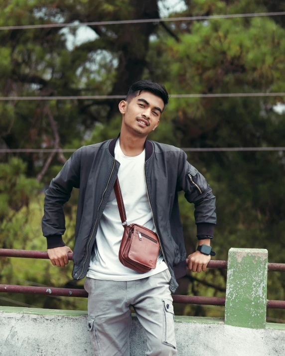 man posing with his hand on the belt, wearing shorts, a white tee and grey jacket