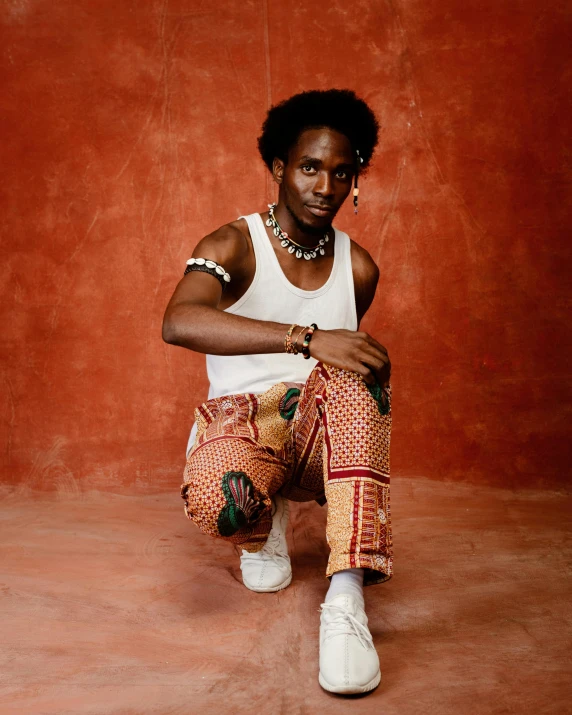 the young black woman is sitting down in front of a red backdrop