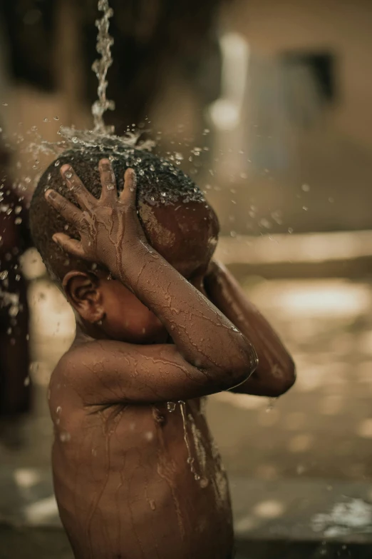 a boy playing in the water with his hand on his face