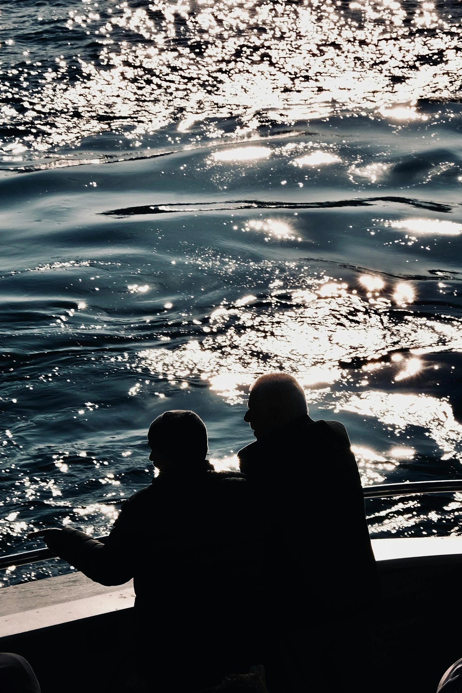 two people sitting on a boat while they look out at the water