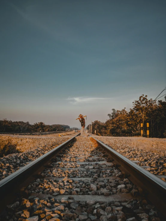 two people standing on the tracks with a sky background