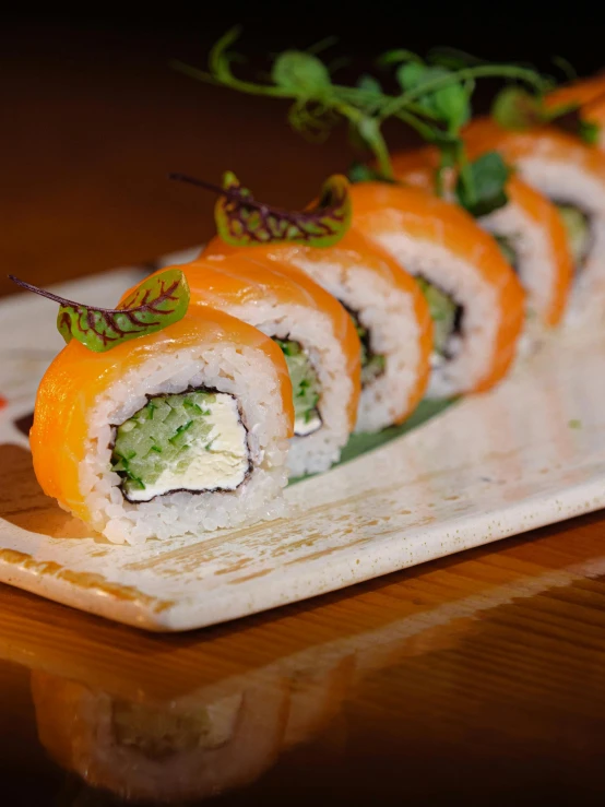 a wooden table holding a white plate with sushi on it