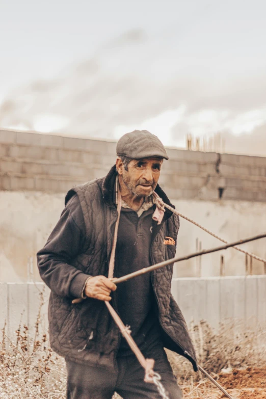 a man walking outside carrying a very long metal stick