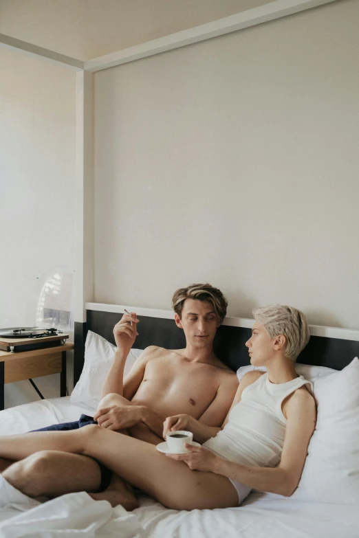 a couple of people sitting on a bed holding drinks