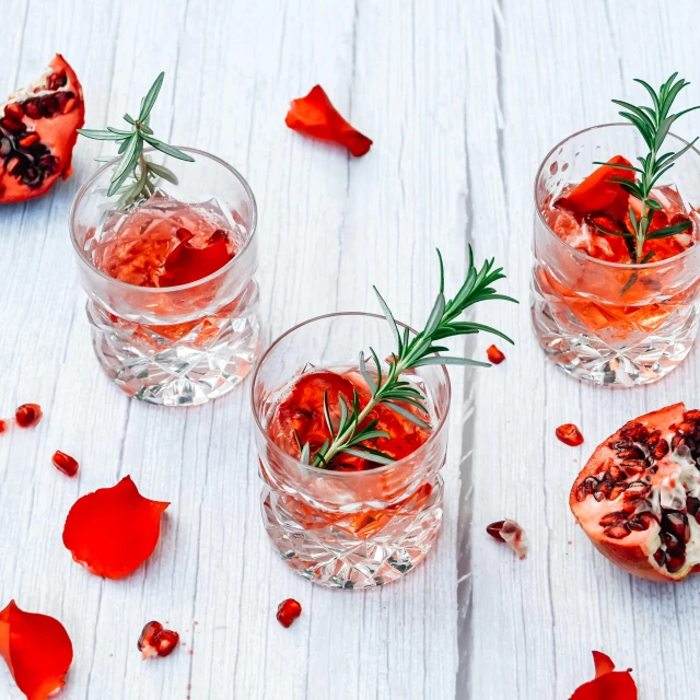 two glasses filled with some type of wine and garnished with herbs