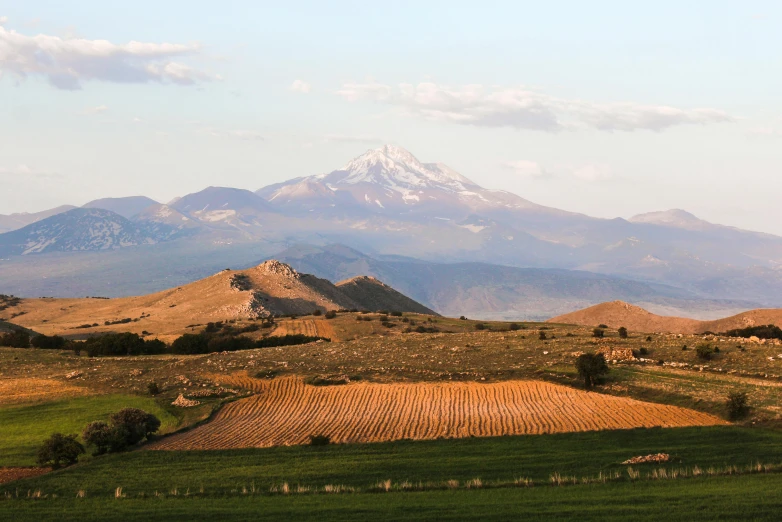 large mountains with fields and a farm under them