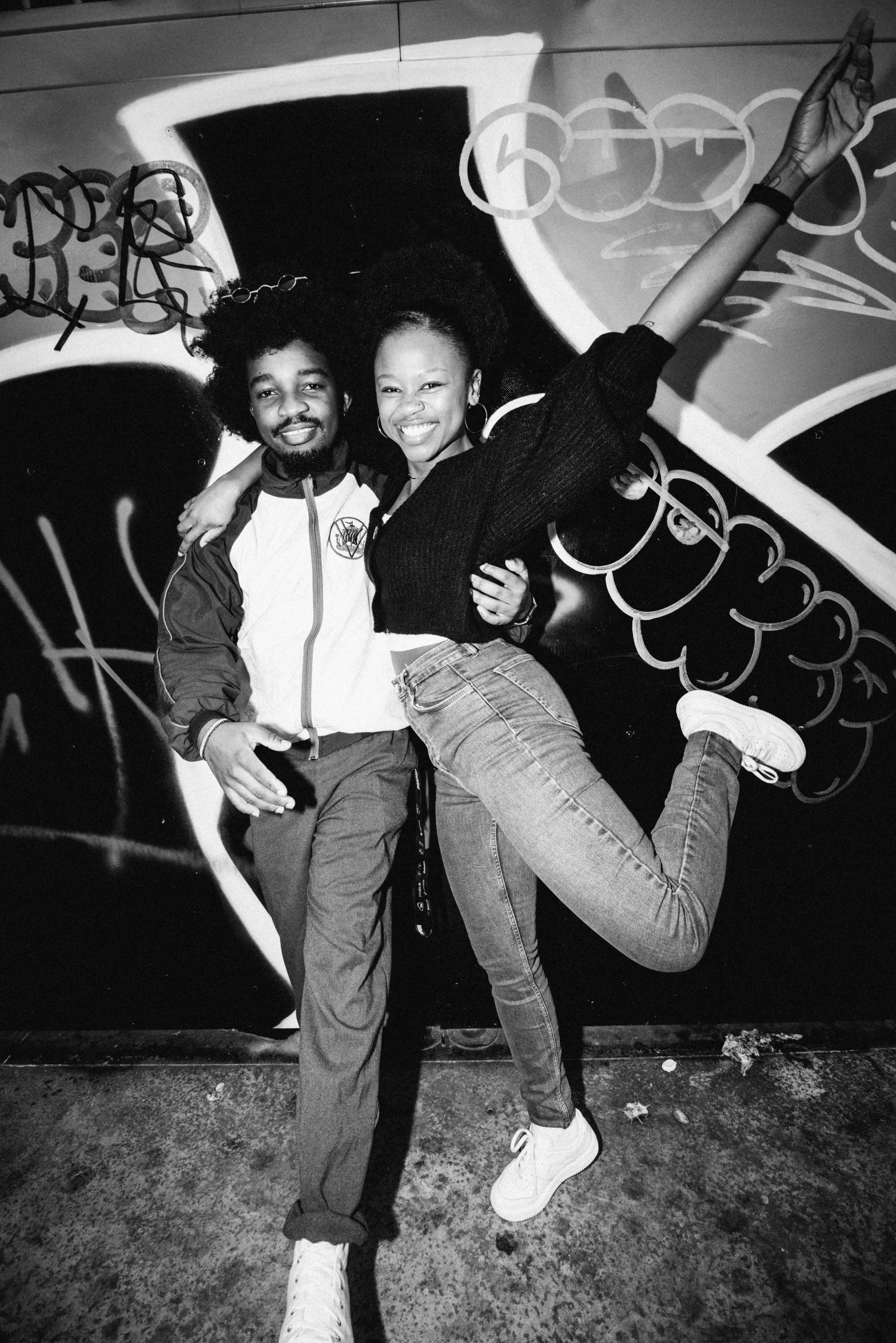 two black people dancing together in front of graffiti