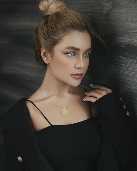 an attractive woman in black posing with a gold necklace