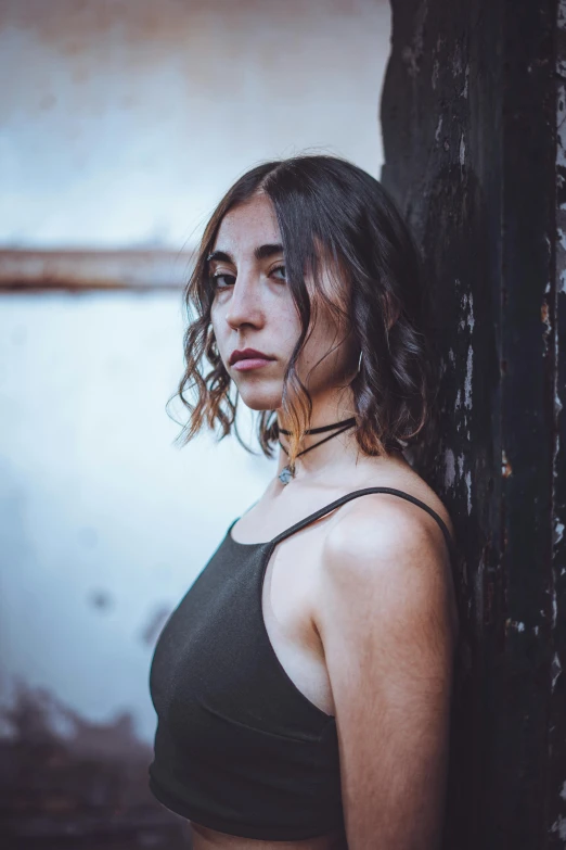 woman in crop top leaning on building corner