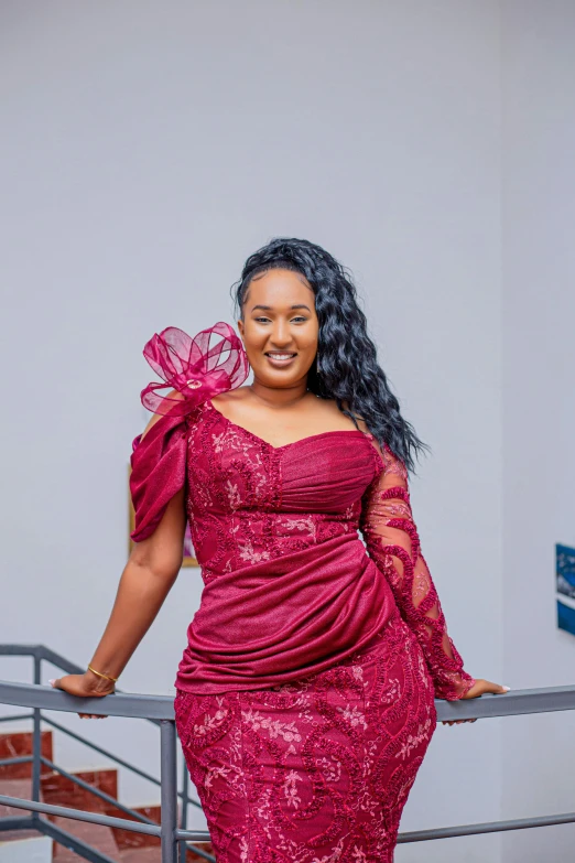 a woman wearing a red dress standing on a railing