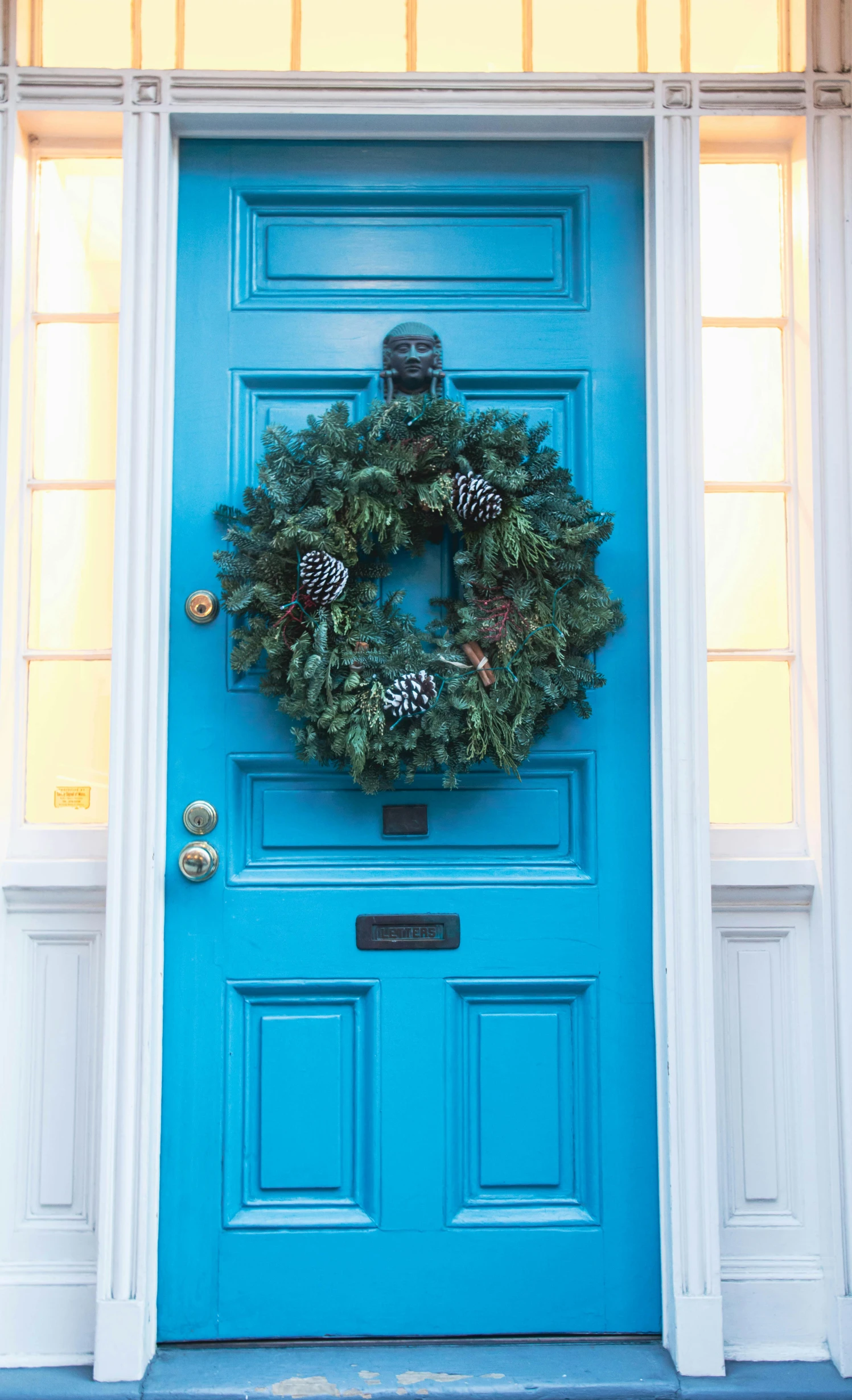 a bright blue door and a wreath hanging from the side of a building