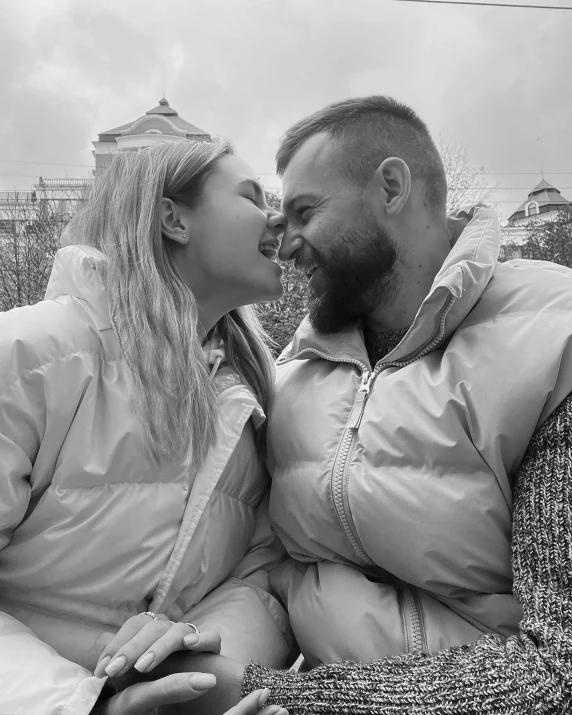 a man and woman kissing on a couch with snow around them