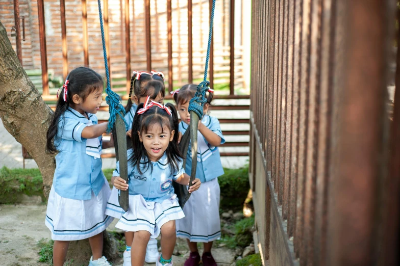 three children hanging on to some kind of thing