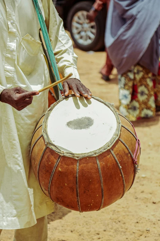 a man holding a drum near another person