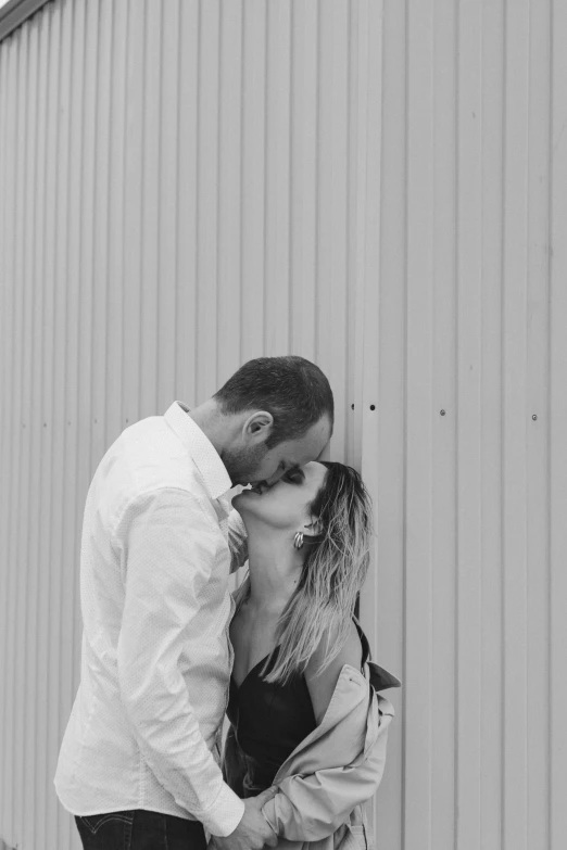 a couple kisses while standing by a building