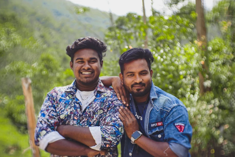 two men smiling with trees and hills in the background