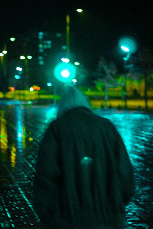 a man standing on the rain in the middle of the street at night