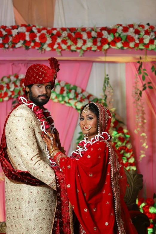 a bride and groom standing in front of pink flowers