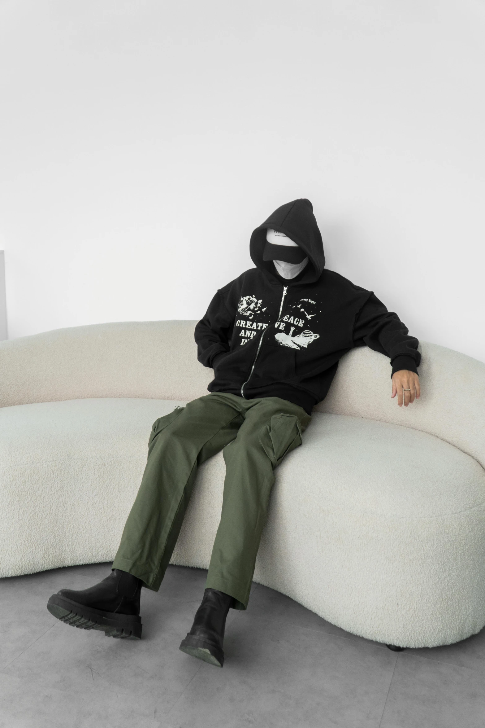 a man with a black hoodie on sitting on a chair