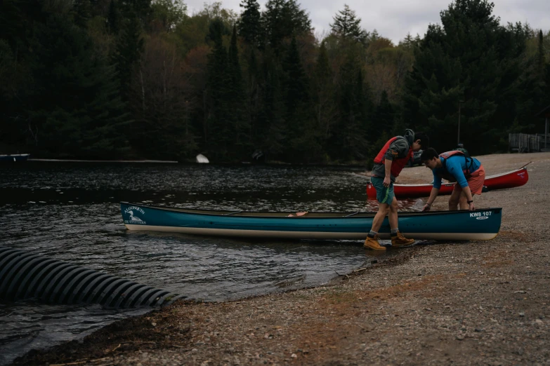 two people with backpacks on standing on a canoe