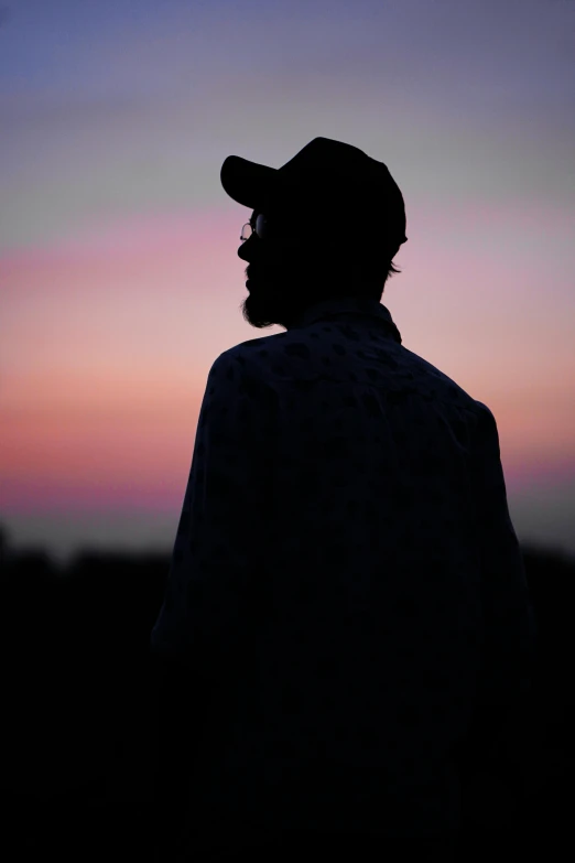 silhouette of a man wearing a baseball hat and watching the sky