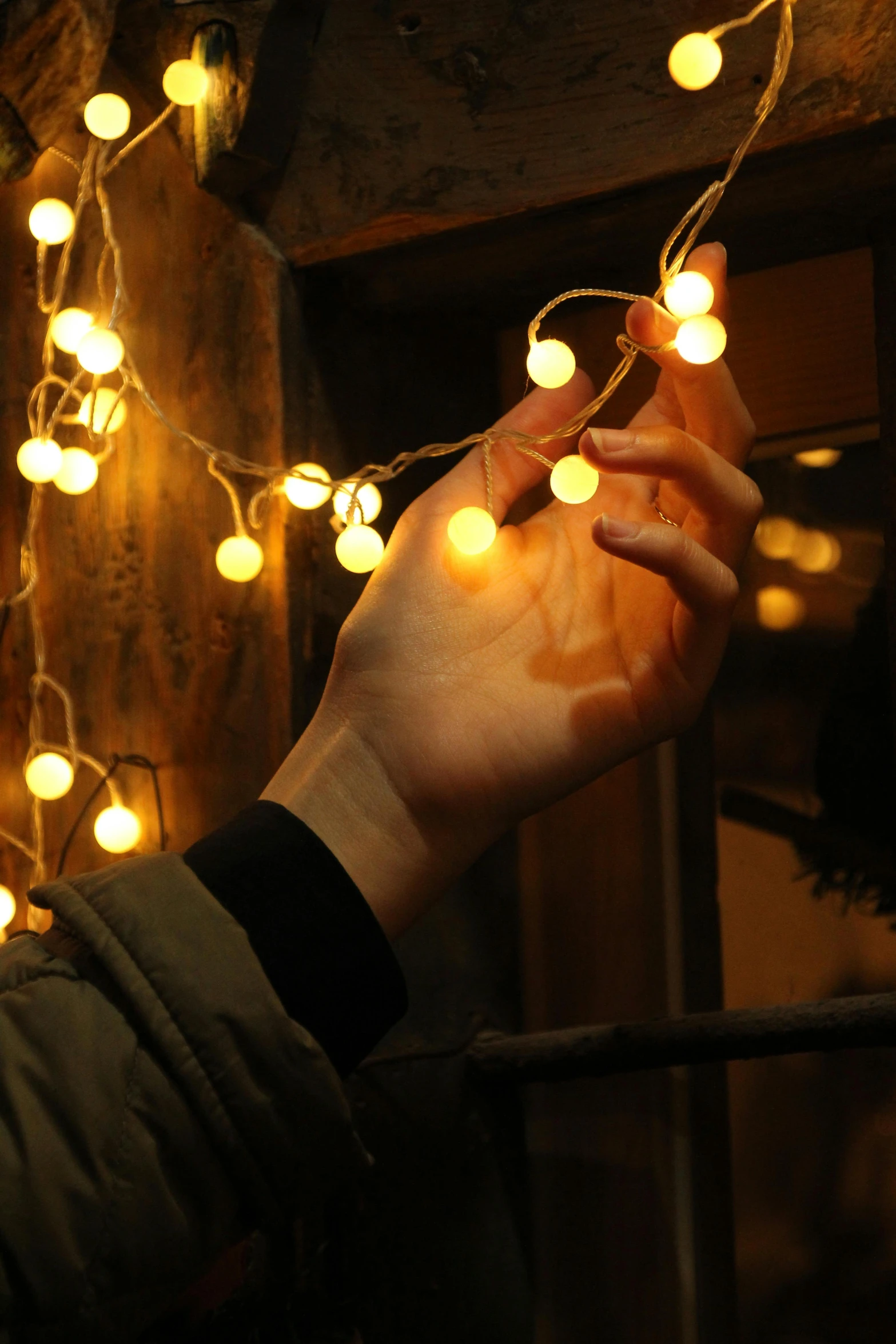 a hand is holding the string of lights on a dark night