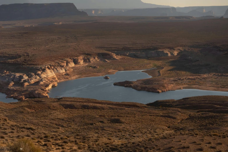 a big open field with a small lake surrounded by mountains