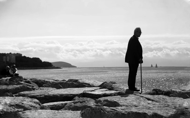 two people stand on rocks looking out at the ocean