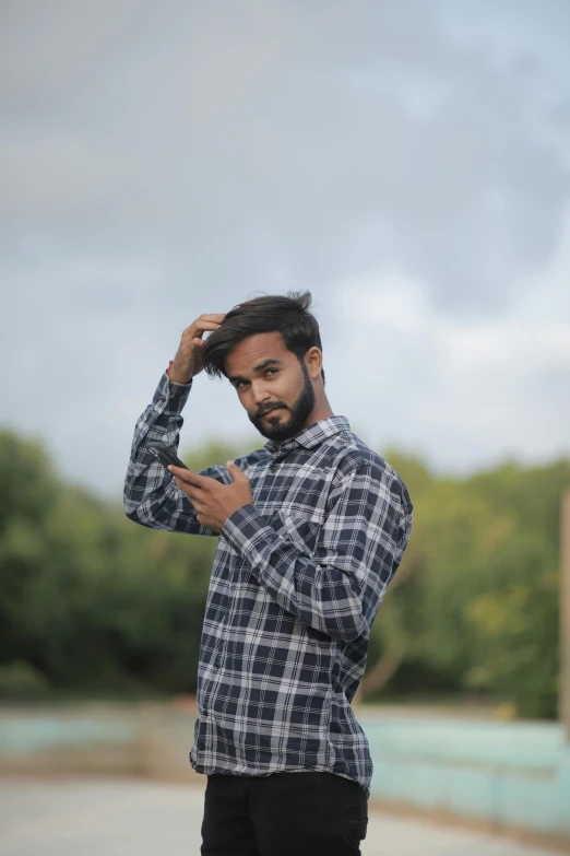 a man with black hair standing near a building holding his hand on his head