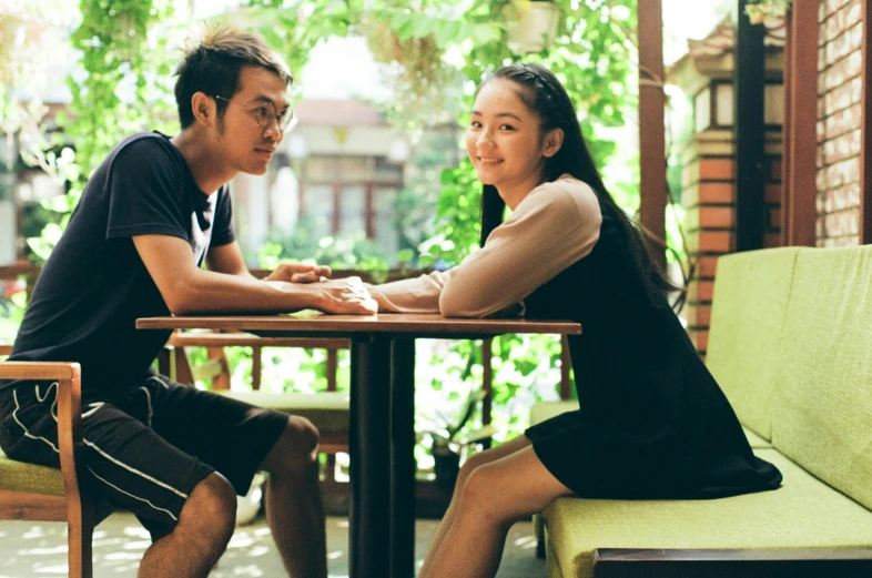 the woman and man sitting at a table are facing each other