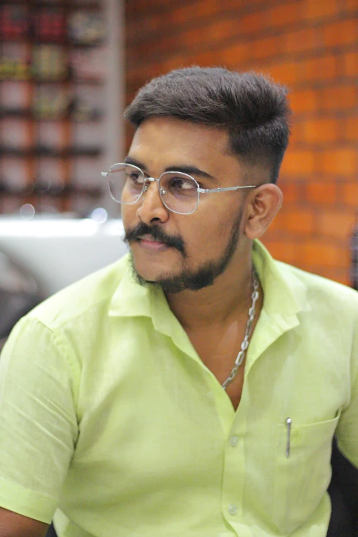 an indian man wearing glasses looks off in to the distance