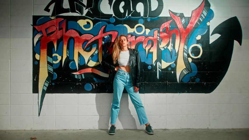 the girl is posing against the wall with her arms behind her back