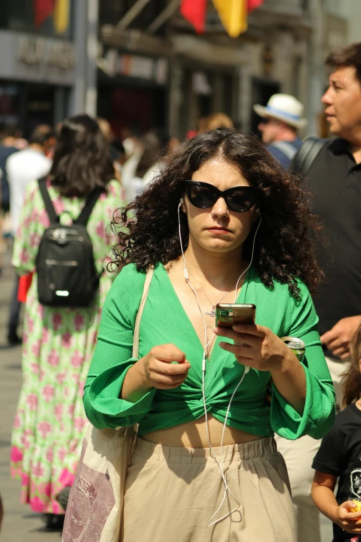 a young woman with curly hair and sunglasses checks her cell phone