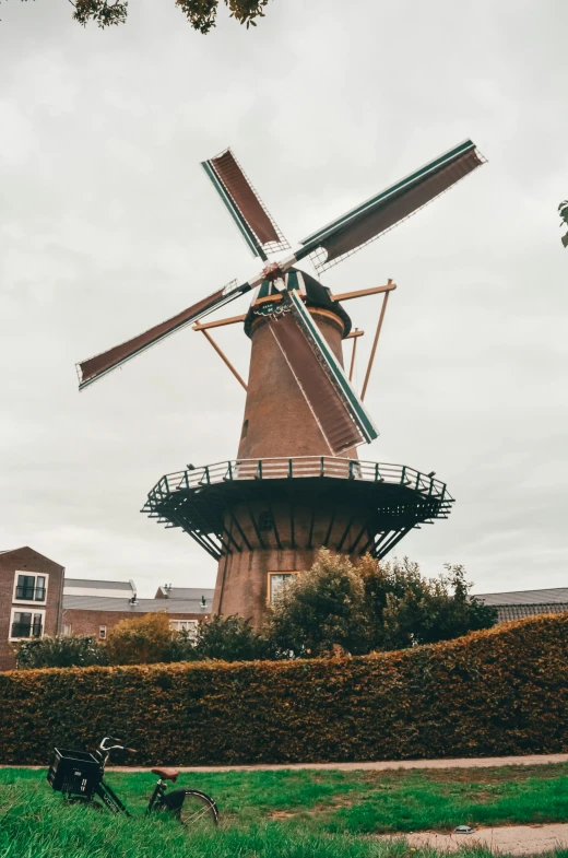 a windmill sits in a field near a green fence