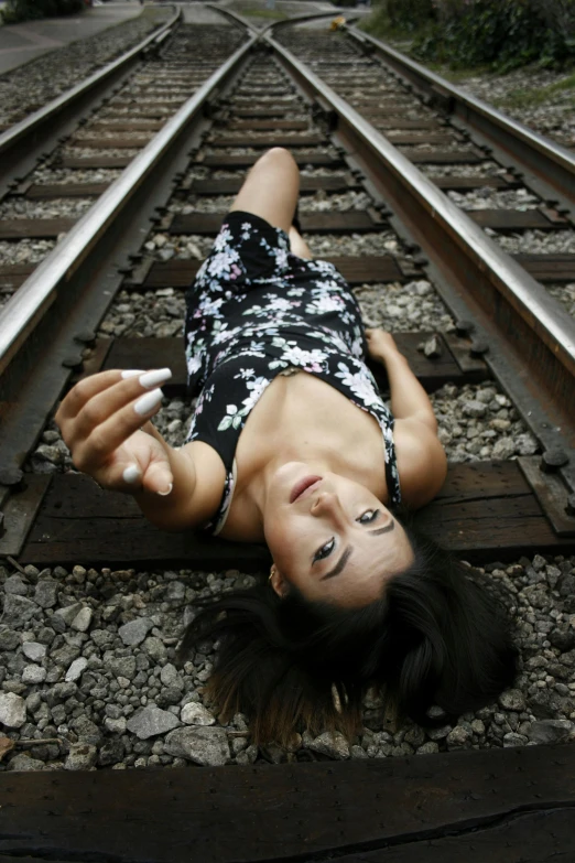 a woman lies on the railway track while smoking a cigarette