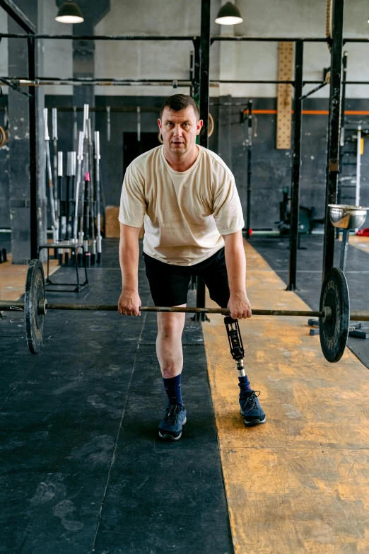 a man holding a barbell with a weight rack behind him