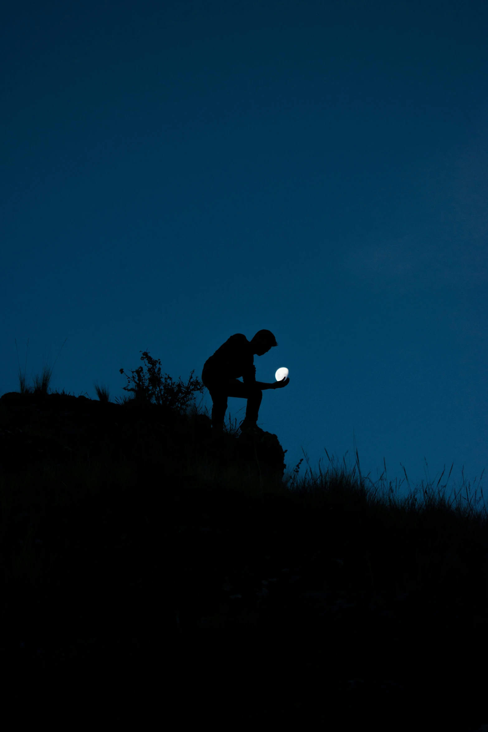 a silhouette of a man looking at a white frisbee at night