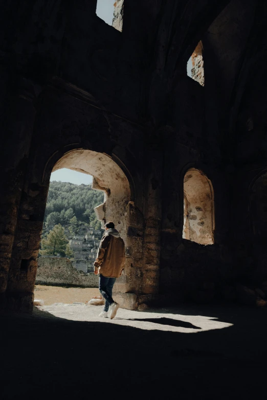 man standing at entrance to stone building, near mountains