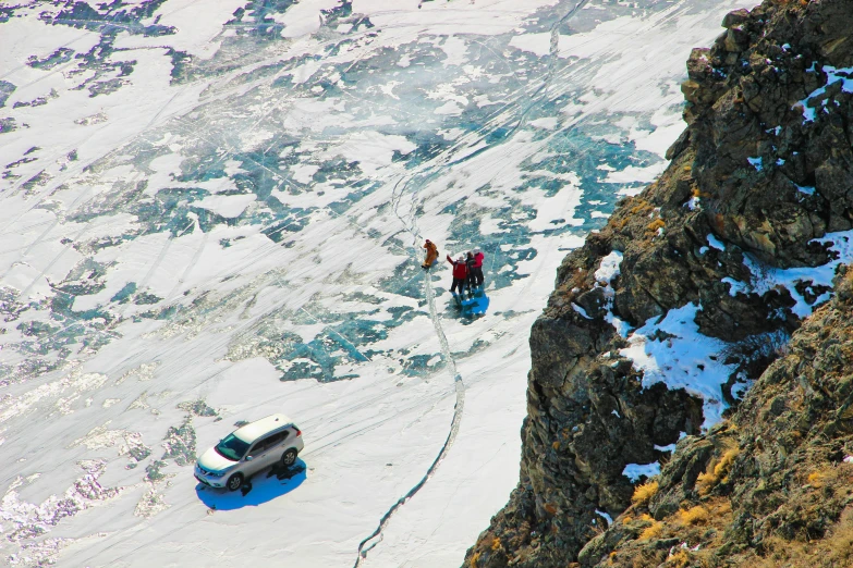 an aerial view of two people walking along the mountain