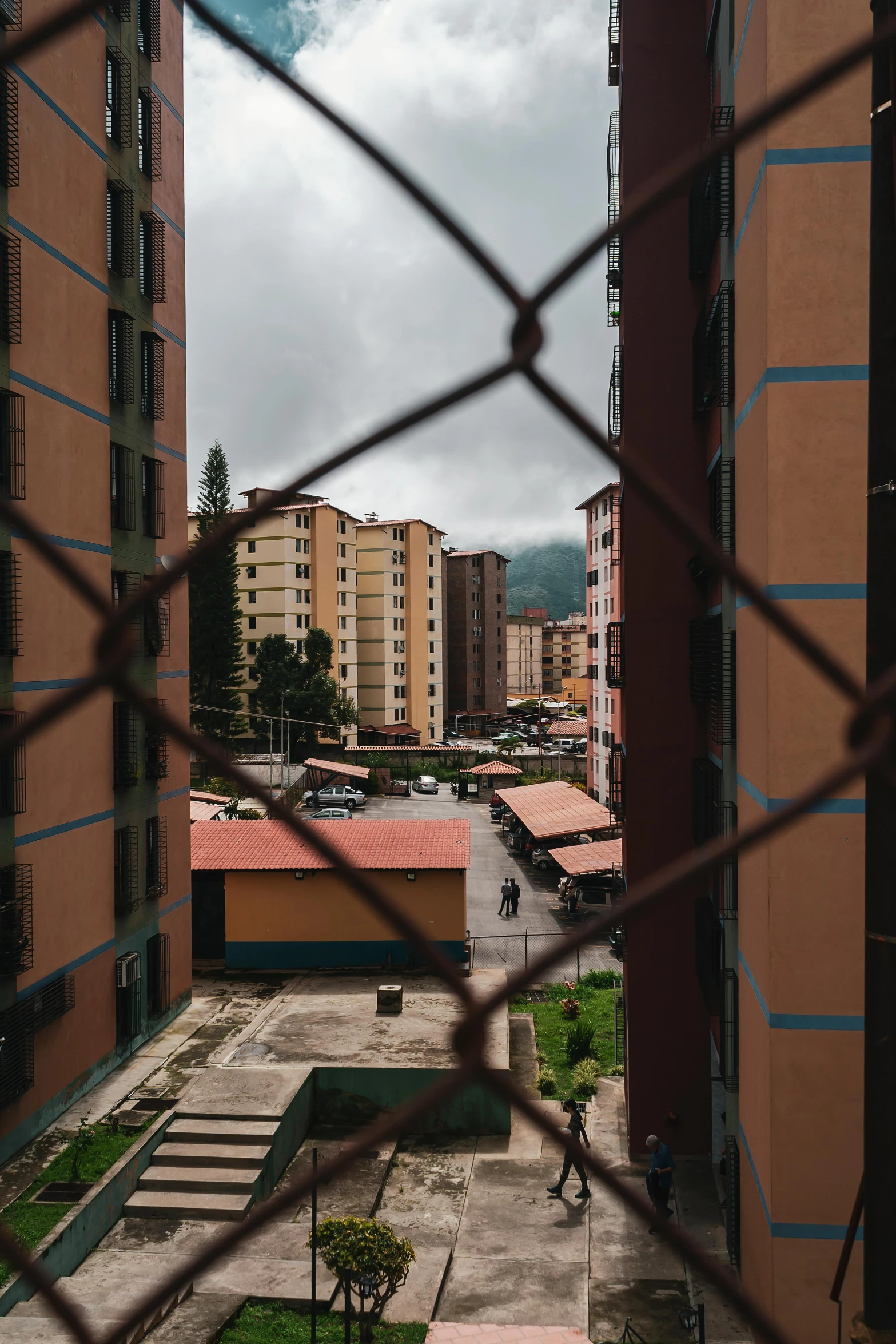 the view from inside of a metal fence looking at buildings