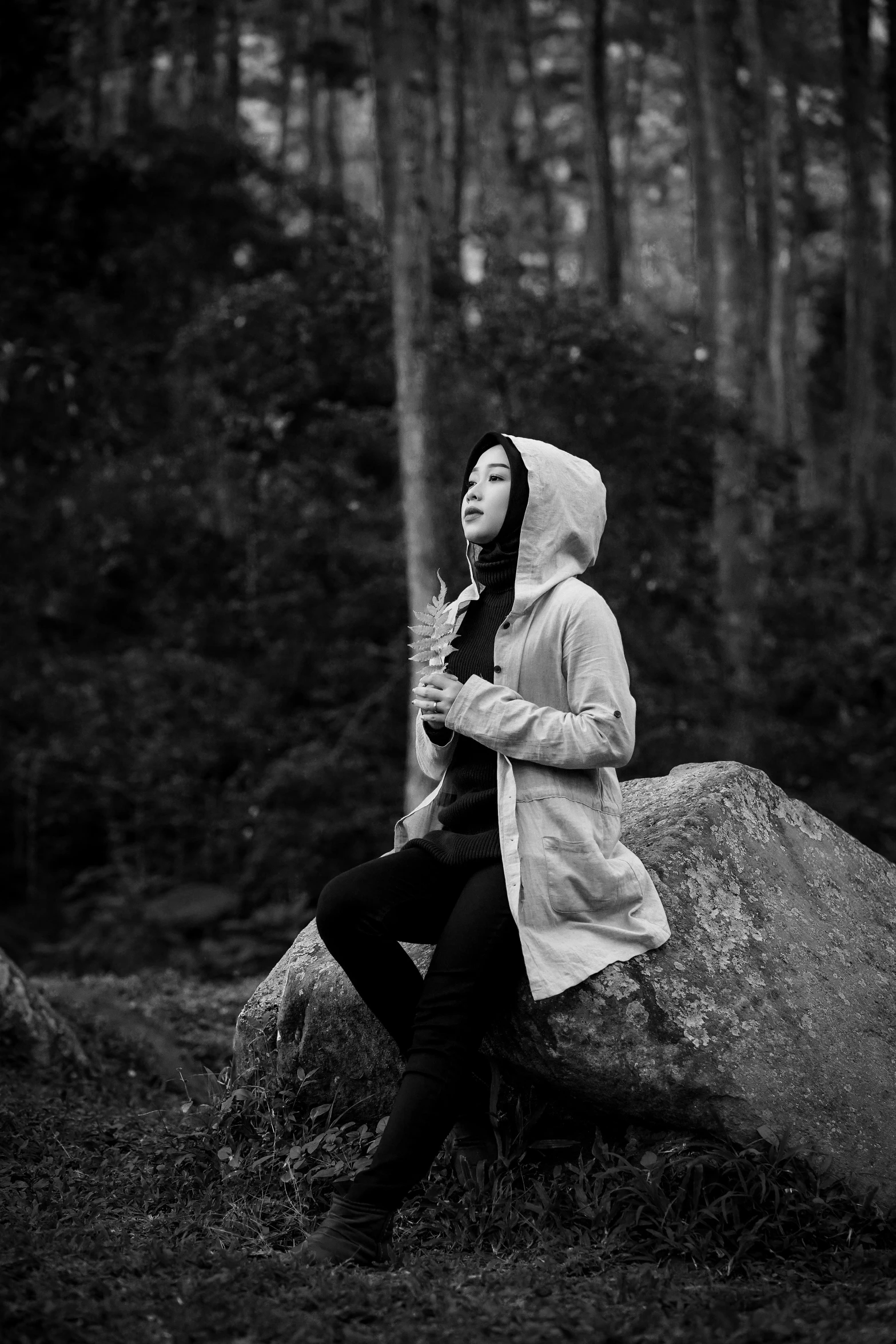 a woman sits on a rock in the woods