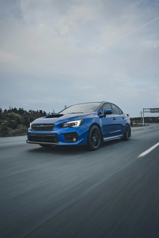 the subaru wrls is blue and is driving down the road