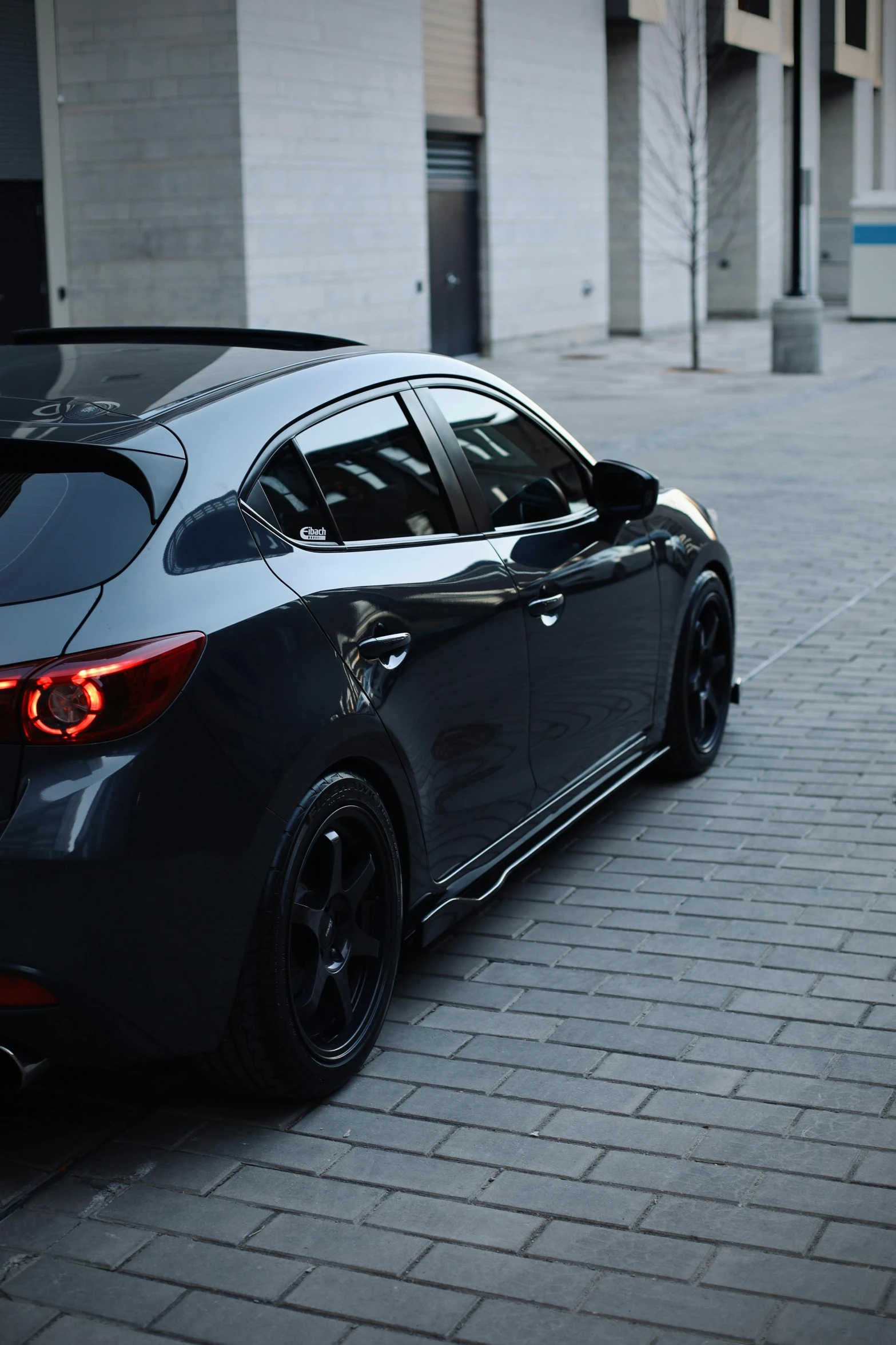 an all black car is parked on a side walk