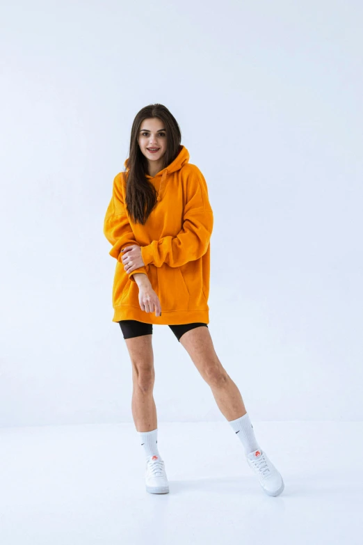 a woman is wearing an orange sweatshirt and white socks